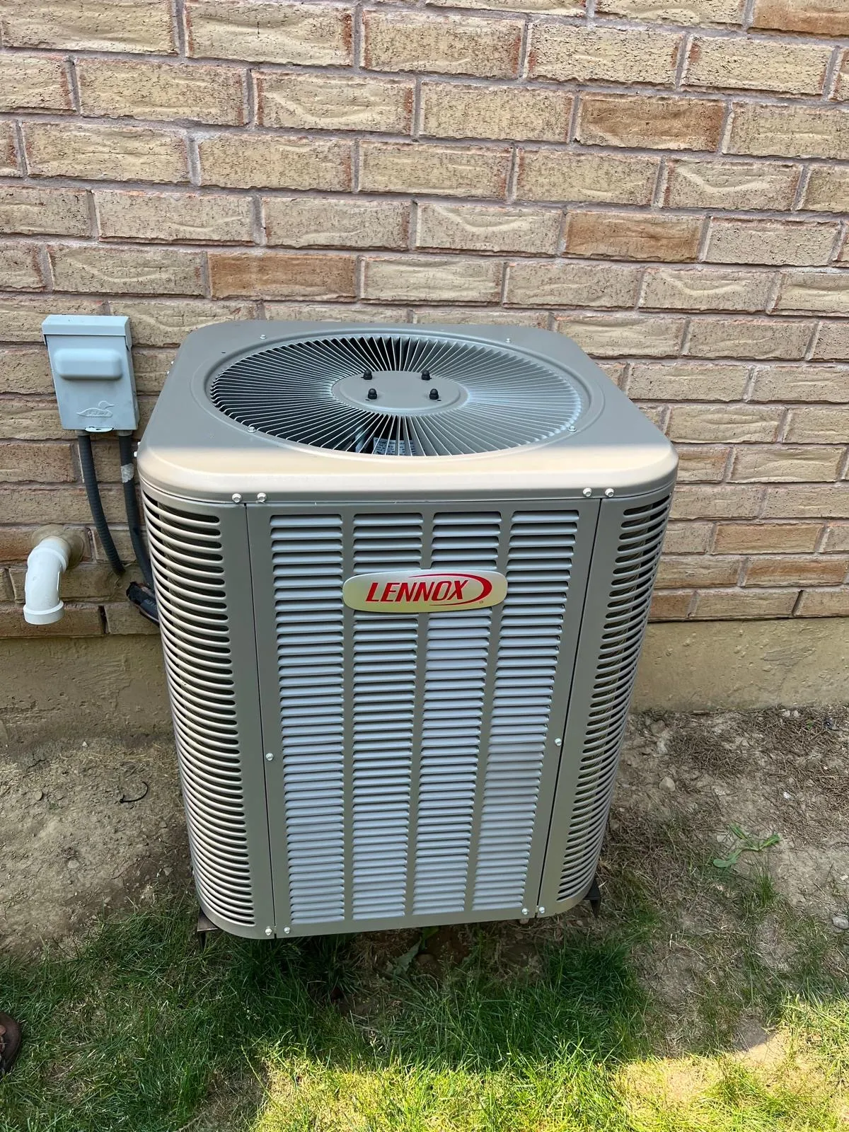 AC condenser installed on a lawn beside a brick GTA home