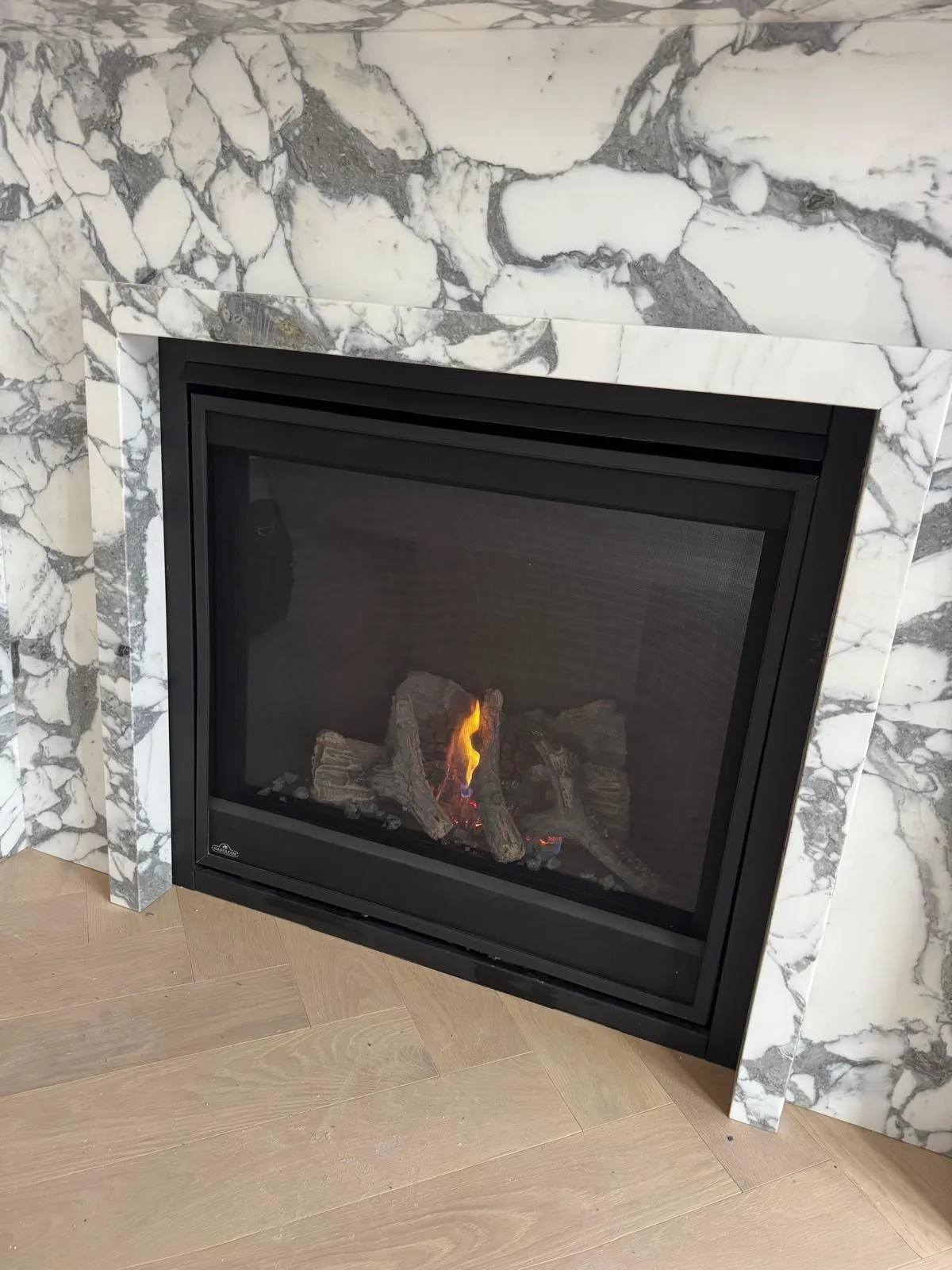 Lit gas fireplace set into a classic marble surround