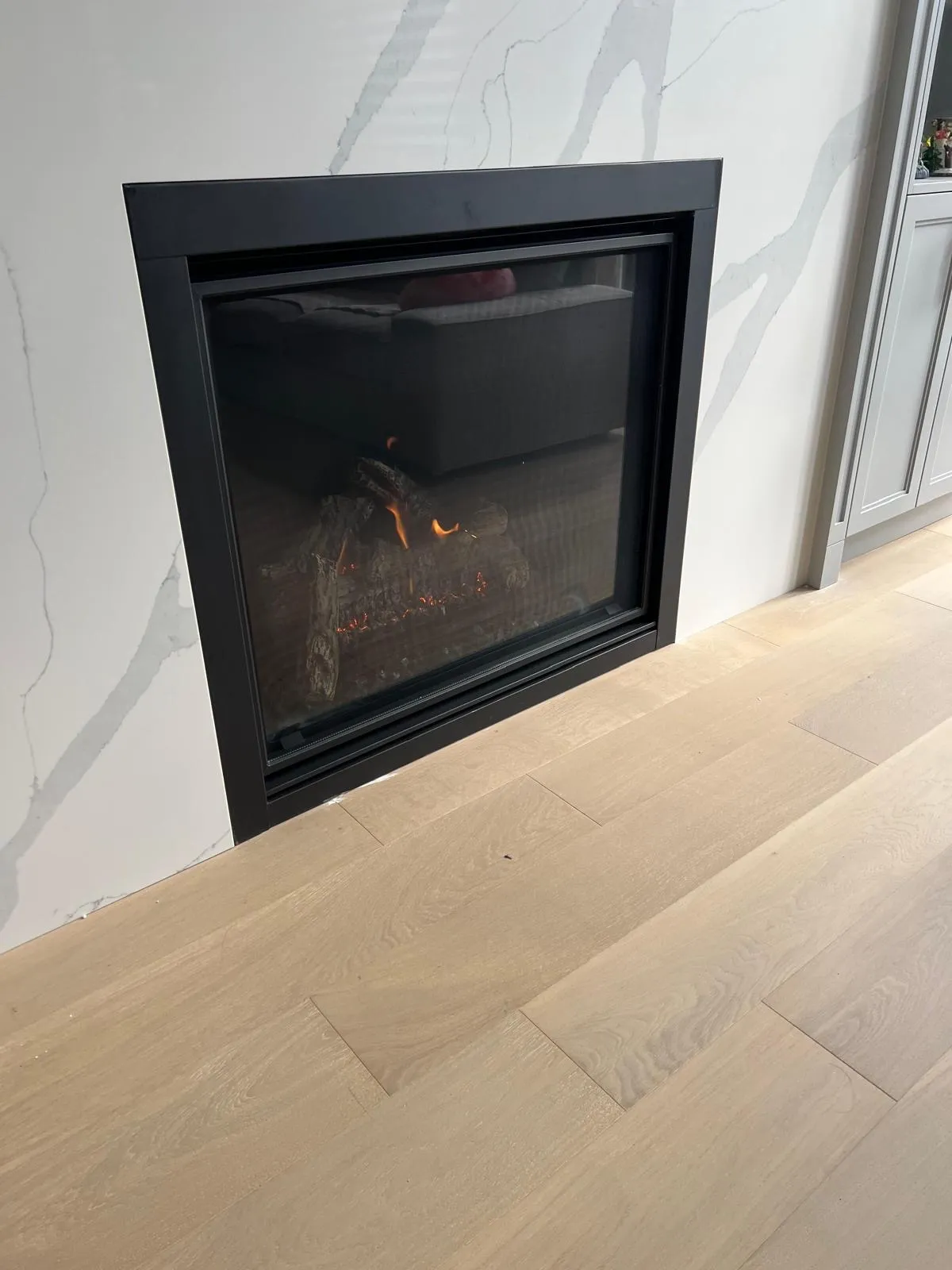 Modern linear fireplace set into a marble feature wall