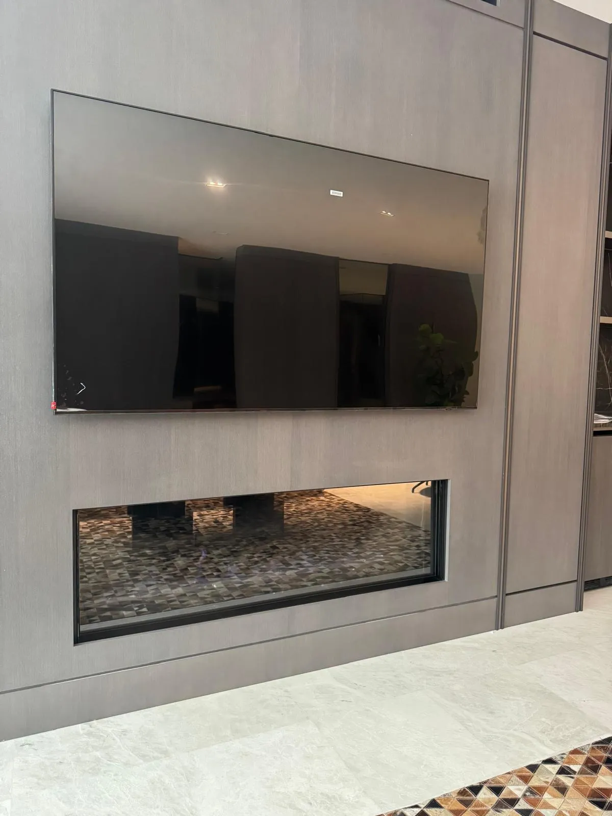 Modern dark linear gas fireplace beneath a wall-mounted TV